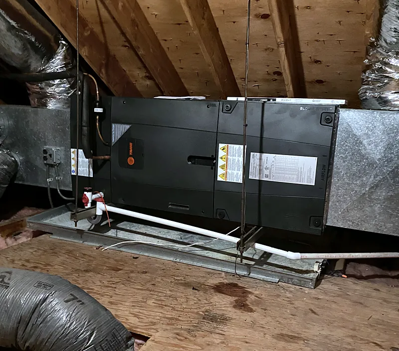 Horizontal air handler installed in an attic, connected to ductwork, with a condensate line