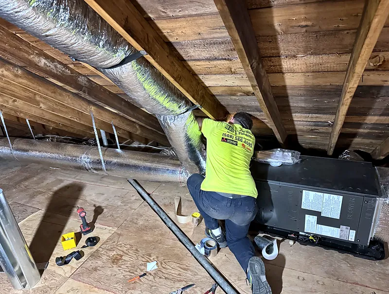 Technician installing an air handler and flexible ductwork in an attic