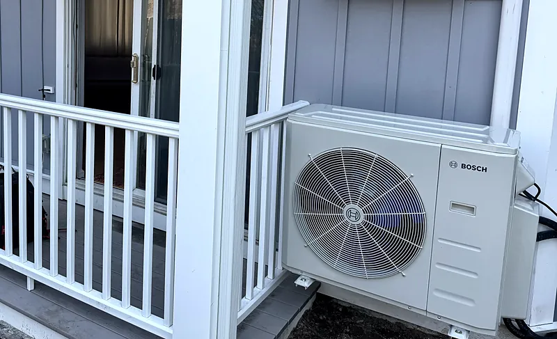 Bosch heat pump outdoor unit beside a porch