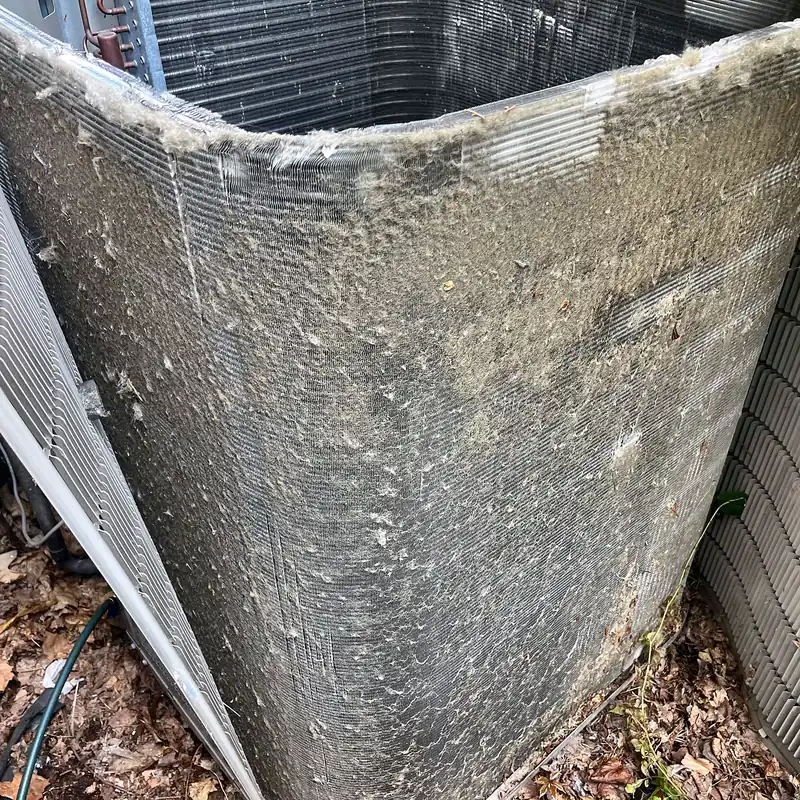 Condenser coil caked in gray lint and debris, with the top off for cleaning