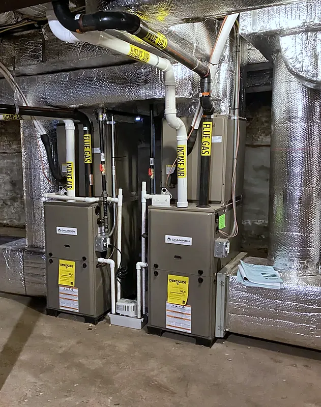 Two high-efficiency gas furnaces with PVC intake and flue piping in a basement