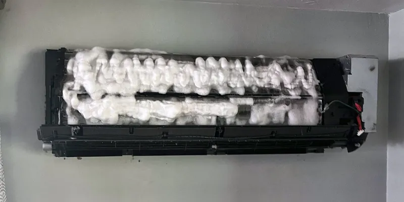 Mini split indoor unit with the cover off and foaming cleaner on the coil