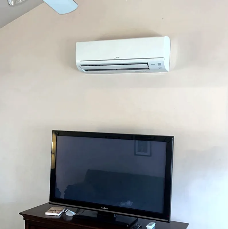 Mitsubishi Electric wall-mounted indoor unit on a living room wall, above a TV