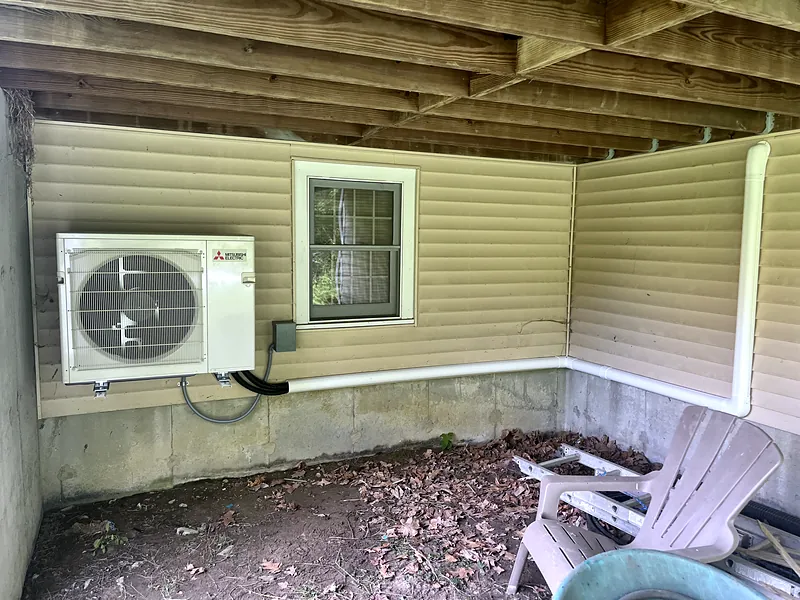 Mitsubishi Electric outdoor unit on a wall bracket under a deck