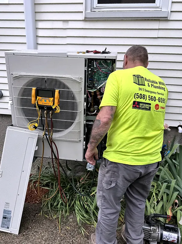 Technician checking refrigerant pressures on an outdoor unit with a digital manifold