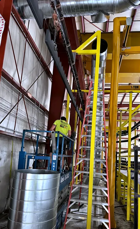 Technician on a scissor lift installing spiral ductwork in a warehouse